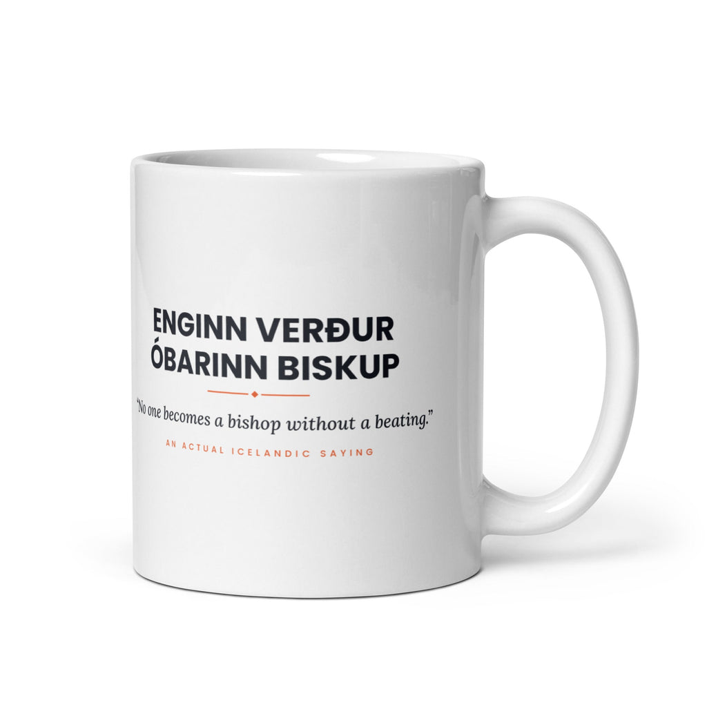 White 11 oz Enginn verður óbarinn biskup mug, handle on the right, showing black lettering, English translation and coral accents.