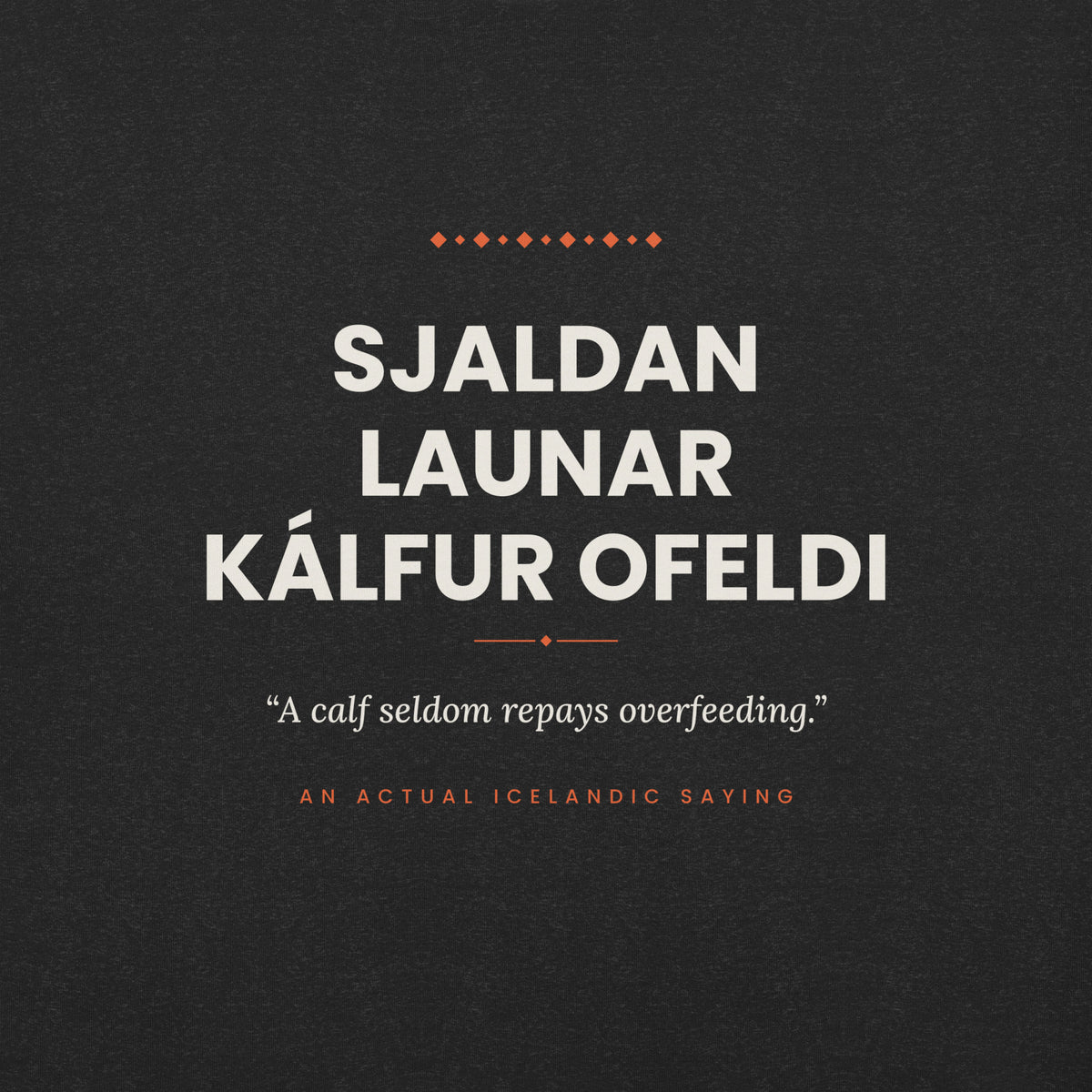 Close-up of the Sjaldan launar kálfur ofeldi front print, showing cream lettering, English translation and coral accents on Black Heather fabric.
