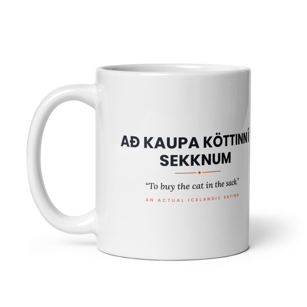 White 11 oz Að kaupa köttinn í sekknum mug, handle on the left, showing the repeated saying on the other side.