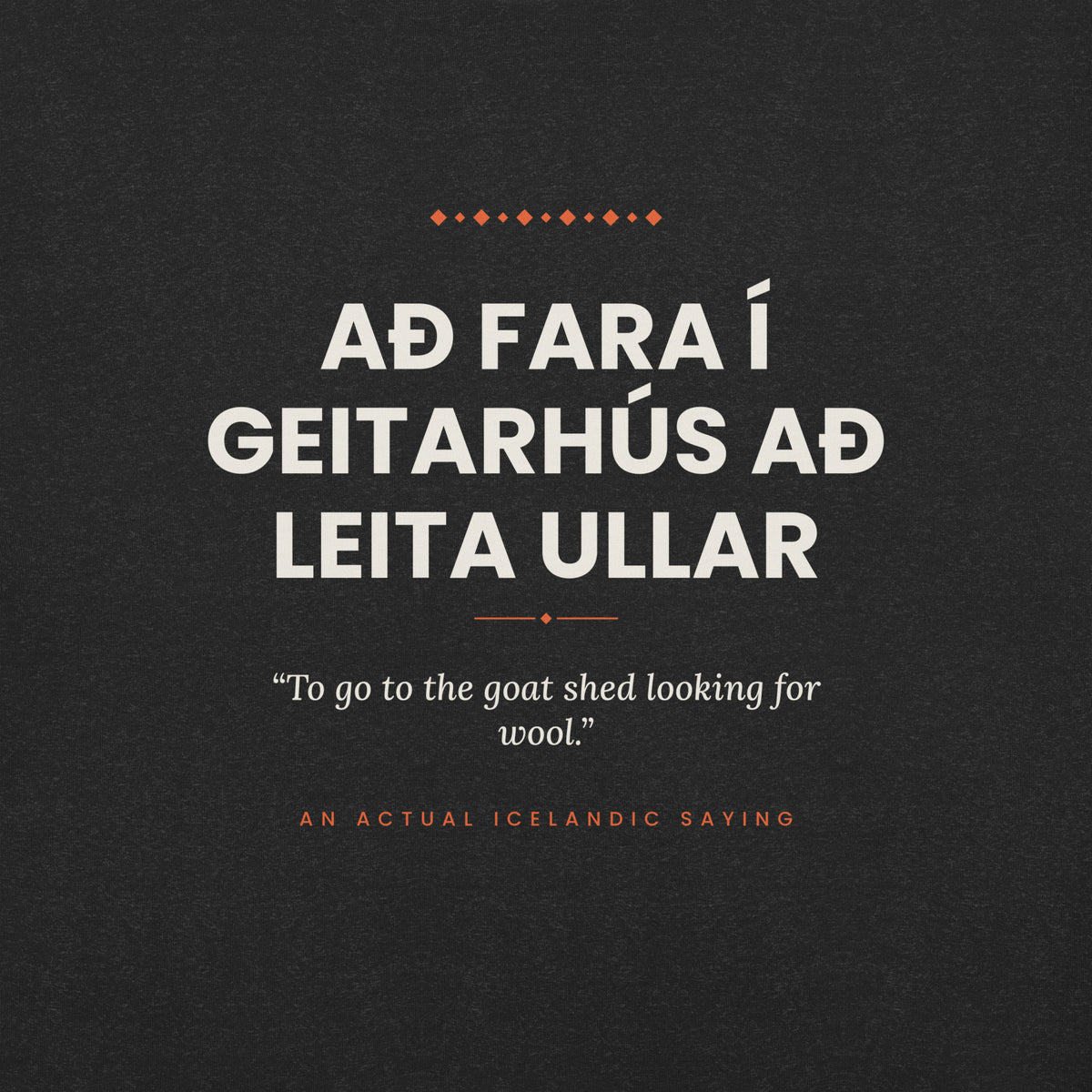 Close-up of the Að fara í geitarhús að leita ullar front print, showing cream lettering, English translation and coral accents on Black Heather fabric.