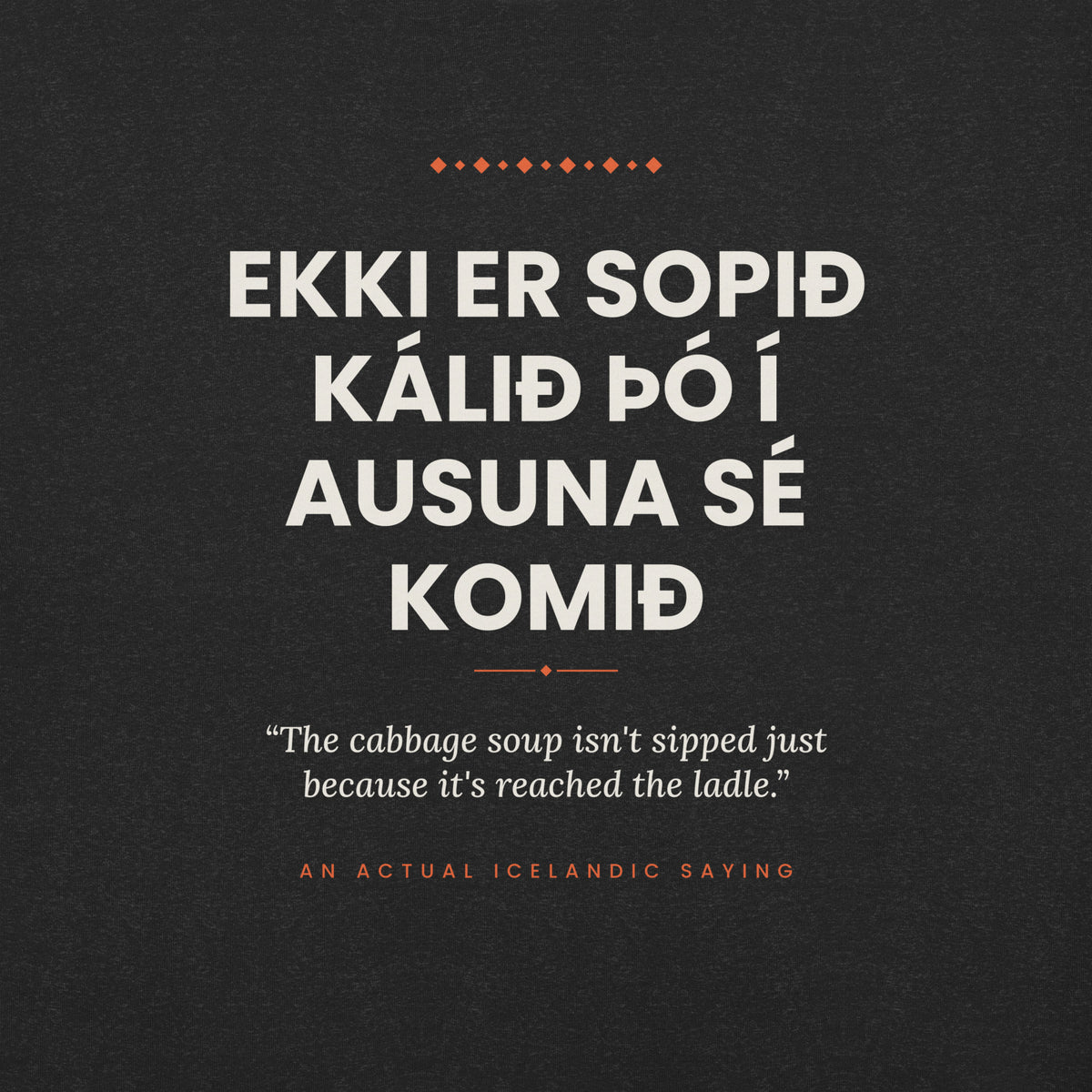 Close-up of the Ekki er sopið kálið þó í ausuna sé komið front print, showing cream lettering, English translation and coral accents on Black Heather fabric.