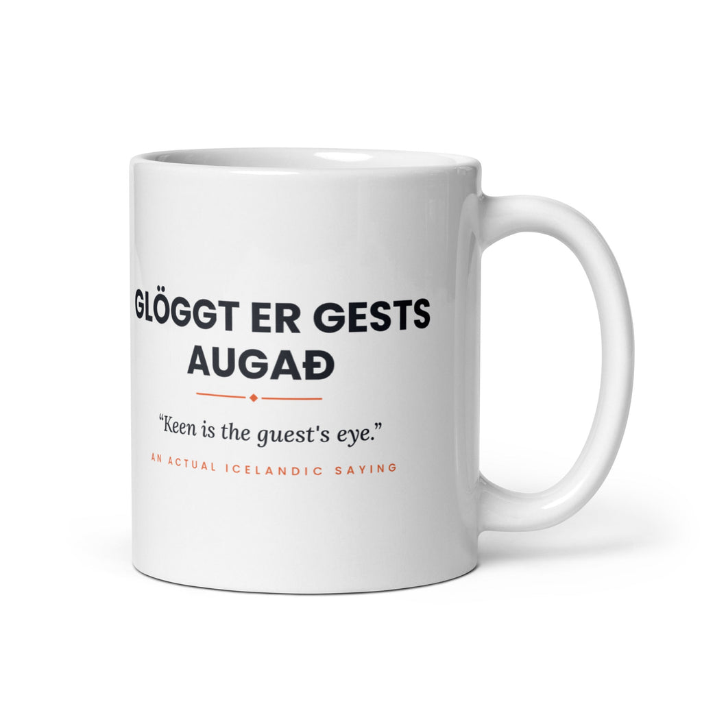 White 11 oz Glöggt er gests augað mug, handle on the right, showing black lettering, English translation and coral accents.