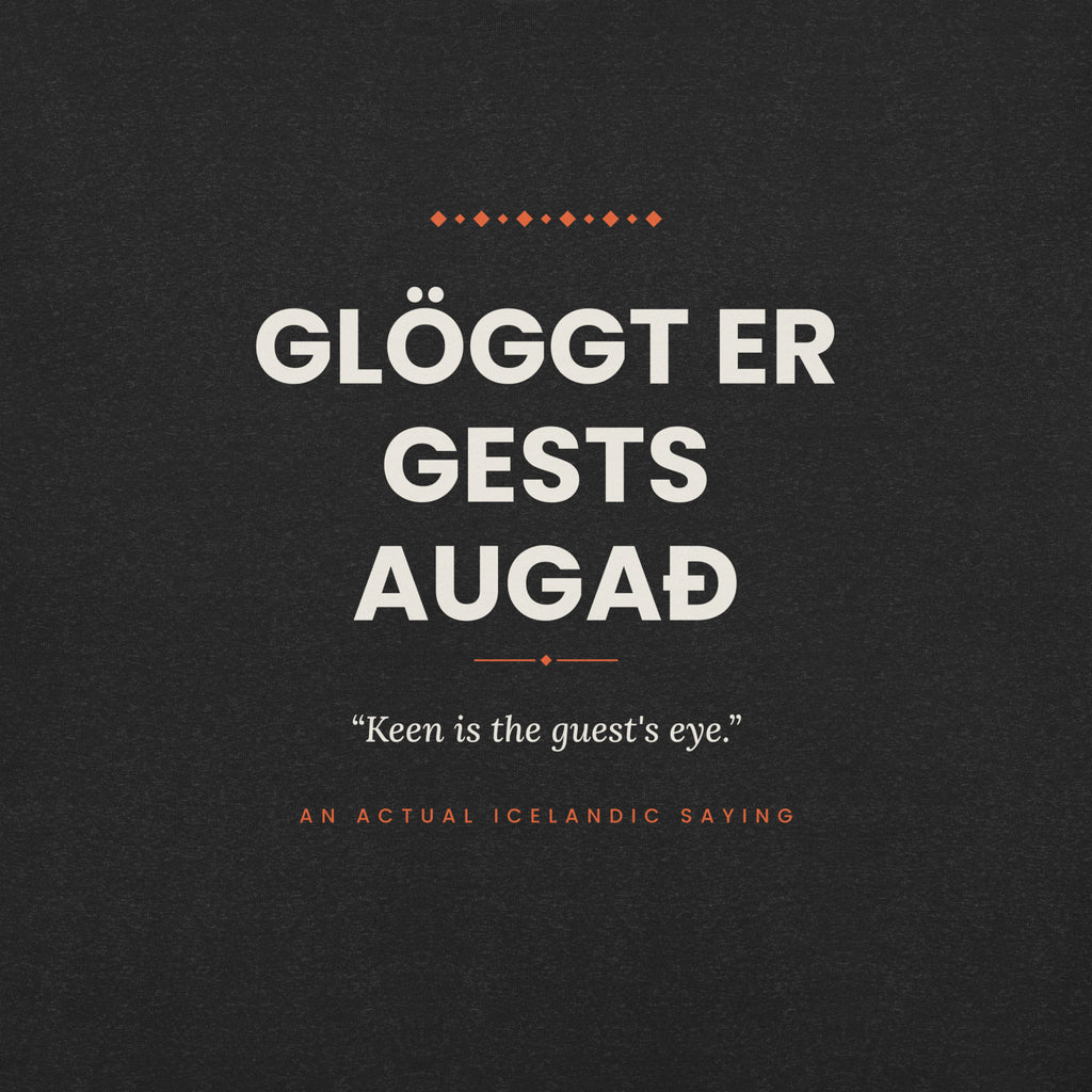 Close-up of the Glöggt er gests augað front print, showing cream lettering, English translation and coral accents on Black Heather fabric.
