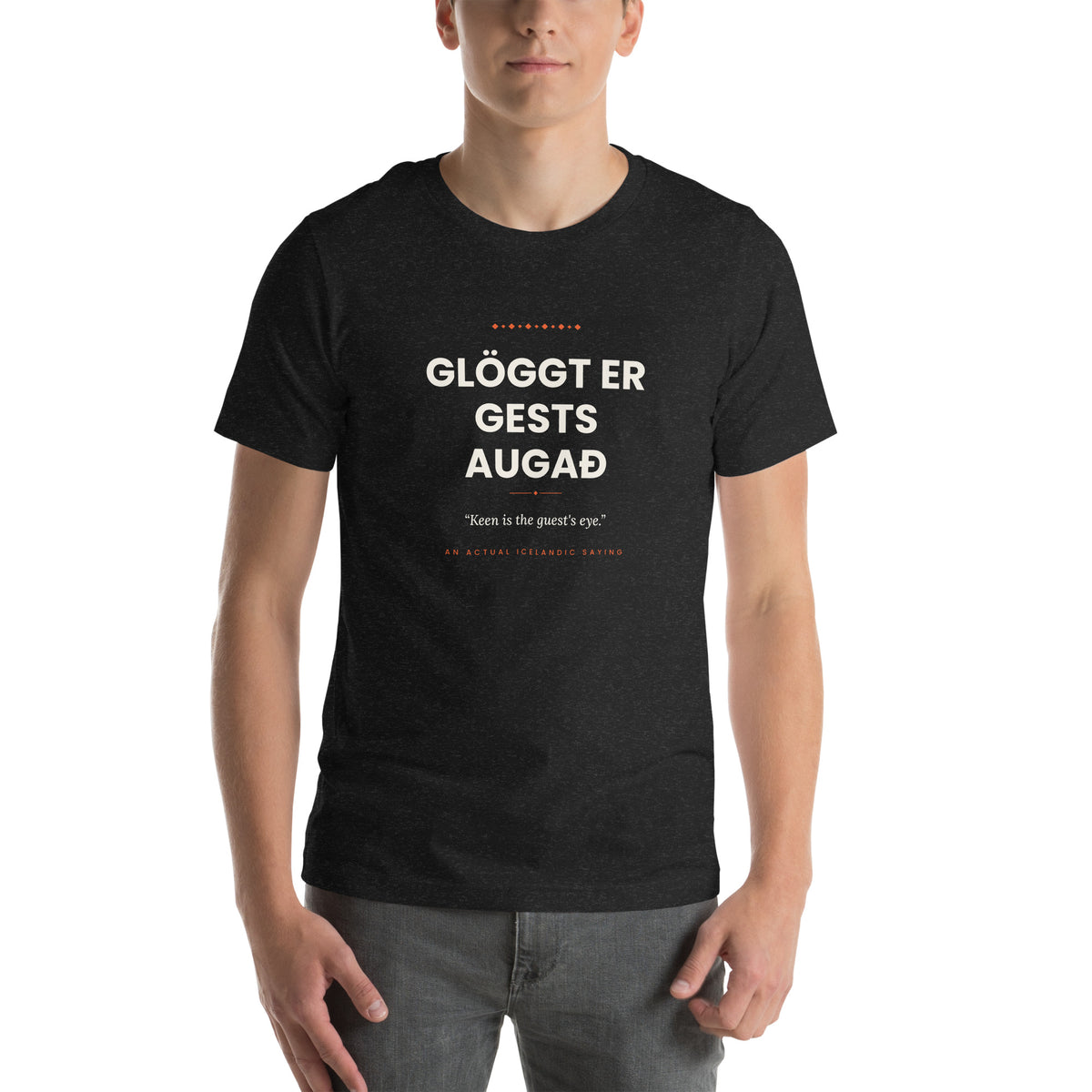 Male model wearing the Black Heather Glöggt er gests augað tee, showing the front print and unisex fit.