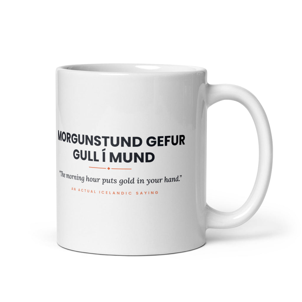 White 11 oz Morgunstund gefur gull í mund mug, handle on the right, showing black lettering, English translation and coral accents.