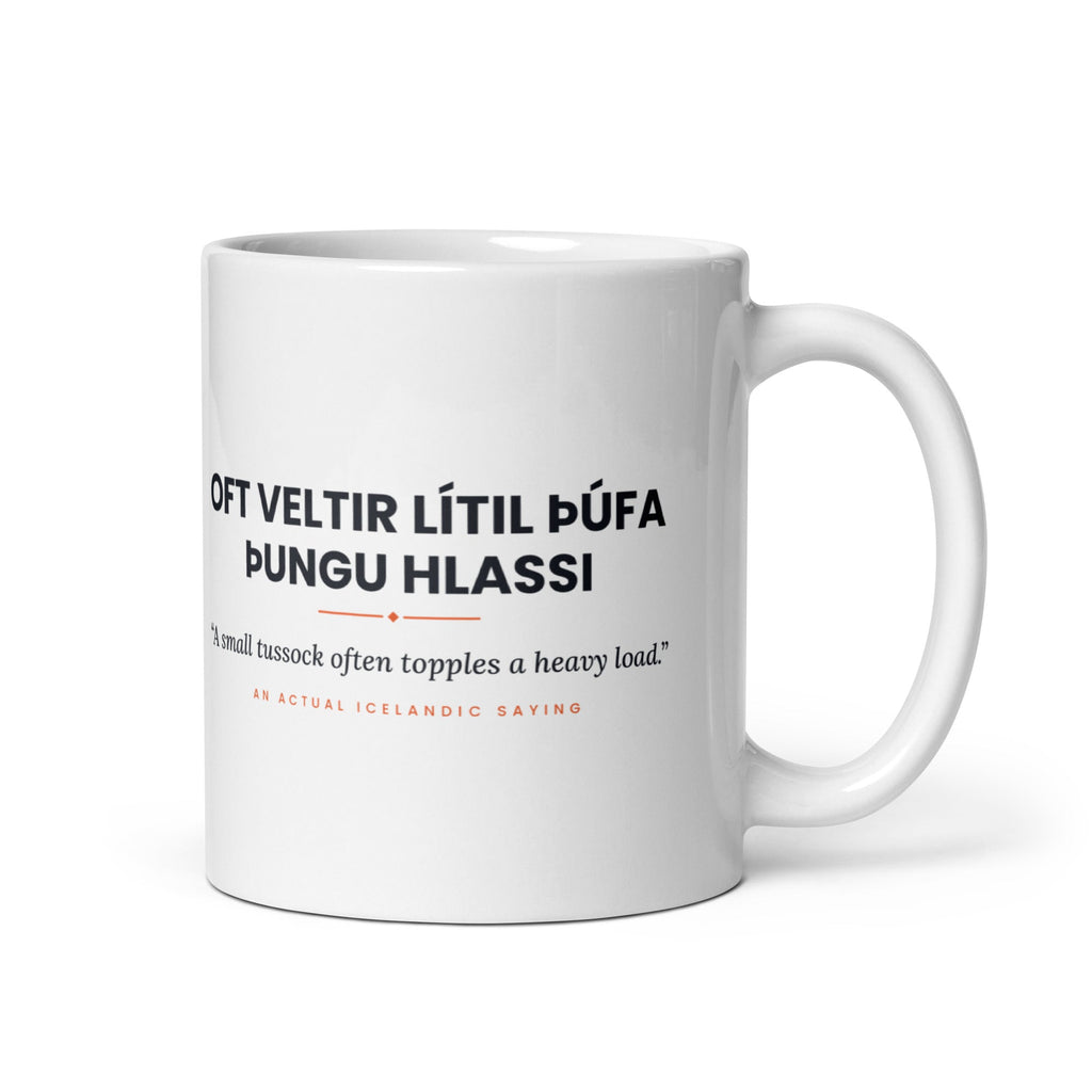 White 11 oz Oft veltir lítil þúfa þungu hlassi mug, handle on the right, showing black lettering, English translation and coral accents.