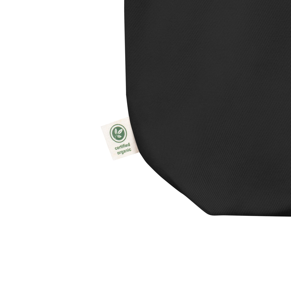 Close-up of the Black Four Seasons. One Hour. tote, showing the bottom seam, woven fabric and side label.