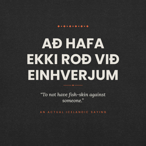 Close-up of the Að hafa ekki roð við einhverjum front print, showing cream lettering, English translation and coral accents on Black Heather fabric.