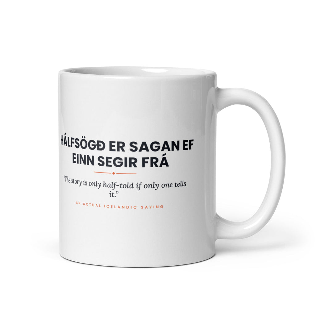 White 11 oz Hálfsögð er sagan ef einn segir frá mug, handle on the right, showing black lettering, English translation and coral accents.