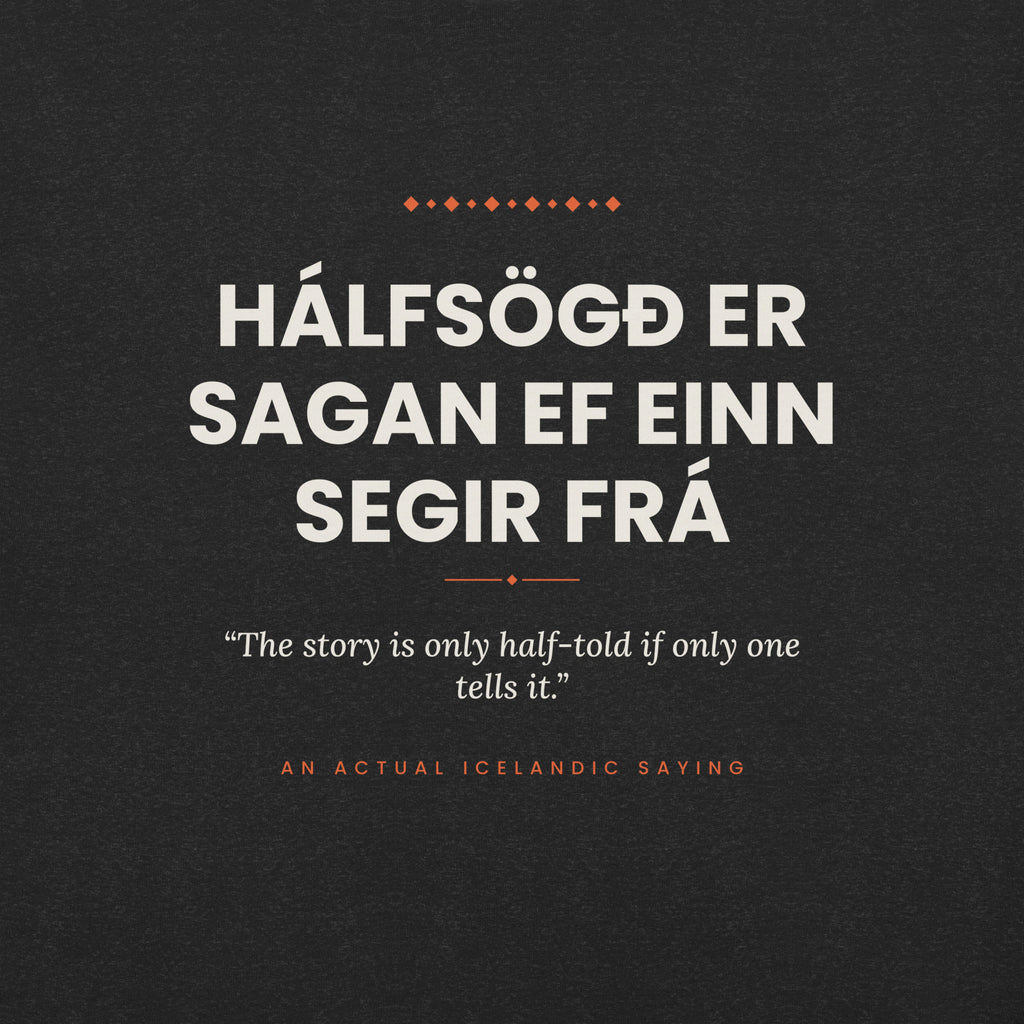Close-up of the Hálfsögð er sagan ef einn segir frá front print, showing cream lettering, English translation and coral accents on Black Heather fabric.