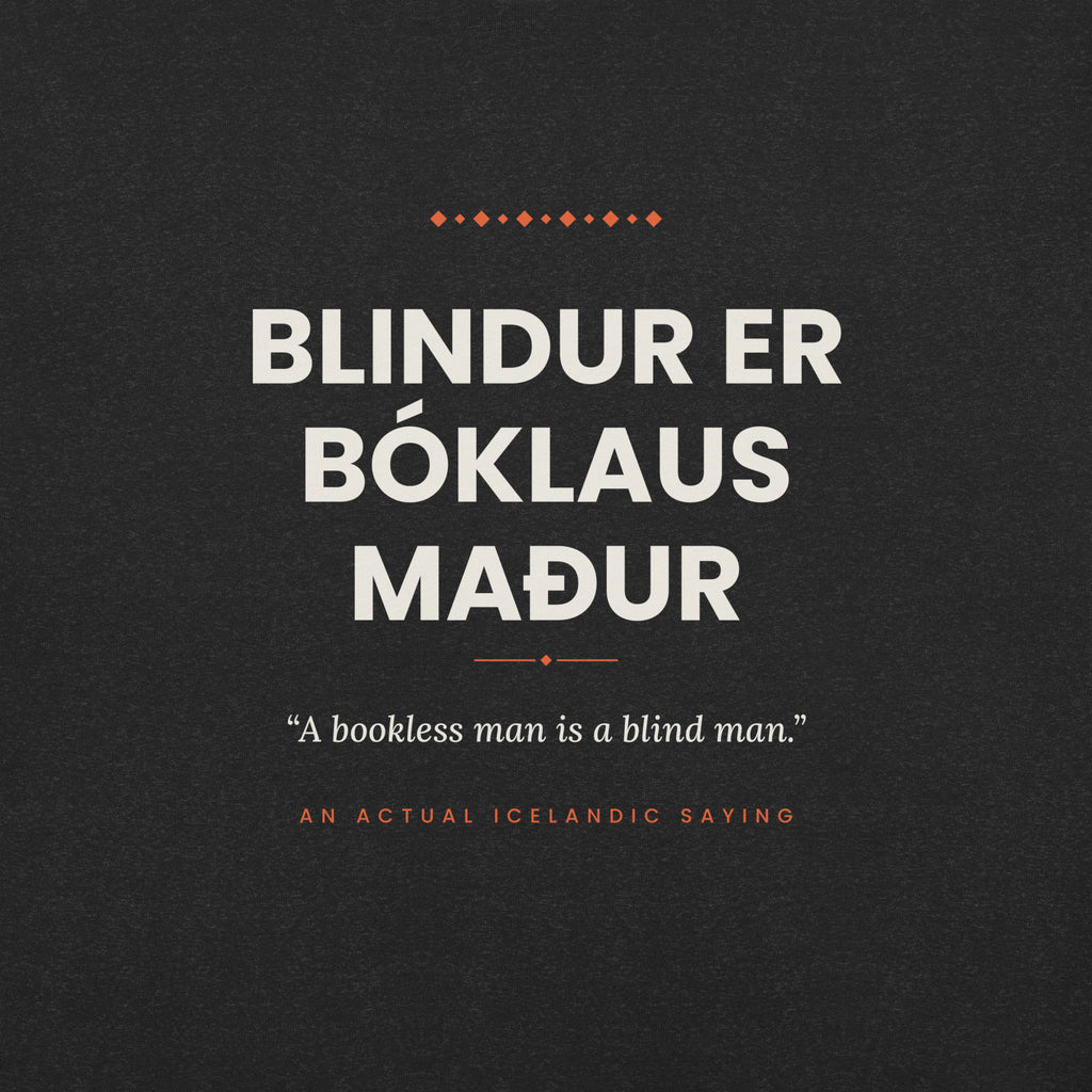 Close-up of the Blindur er bóklaus maður front print, showing cream lettering, English translation and coral accents on Black Heather fabric.
