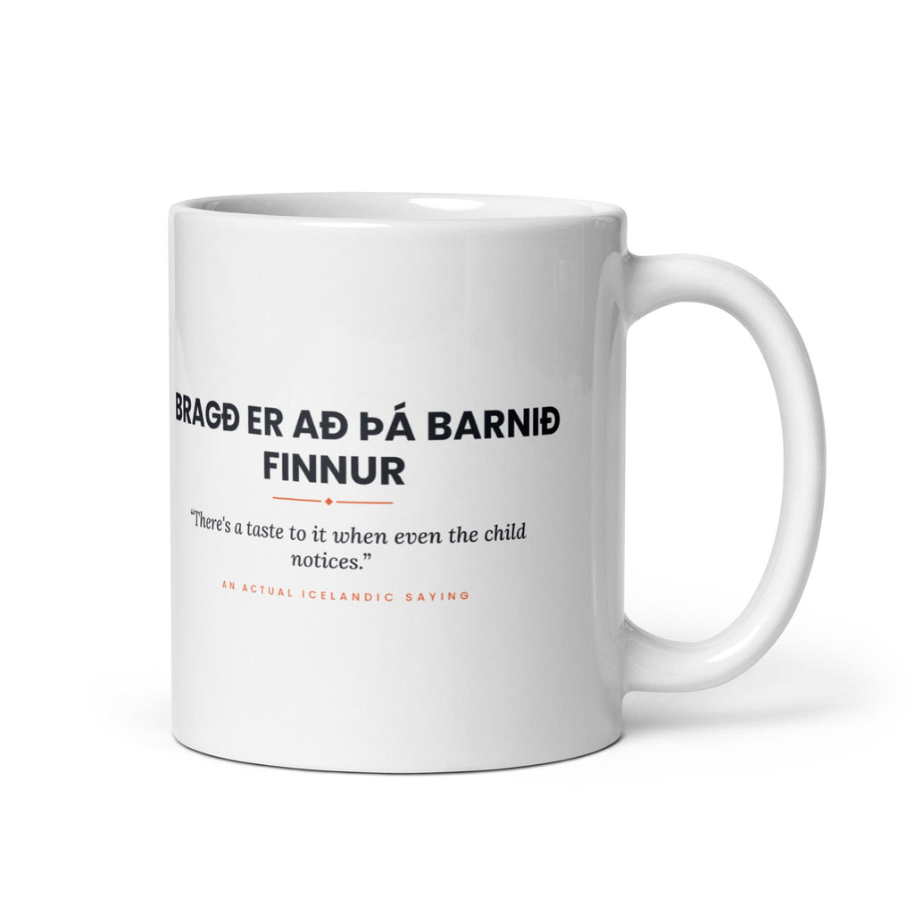White 11 oz Bragð er að þá barnið finnur mug, handle on the right, showing black lettering, English translation and coral accents.
