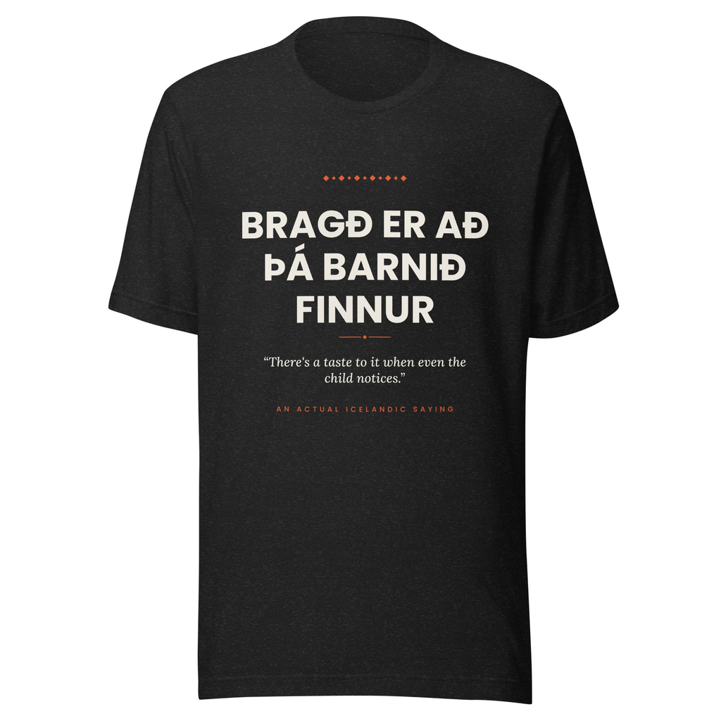 Front view of the Black Heather Bragð er að þá barnið finnur tee, with cream lettering, English translation and coral accents.