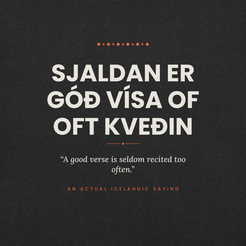 Close-up of the Sjaldan er góð vísa of oft kveðin front print, showing cream lettering, English translation and coral accents on Black Heather fabric.
