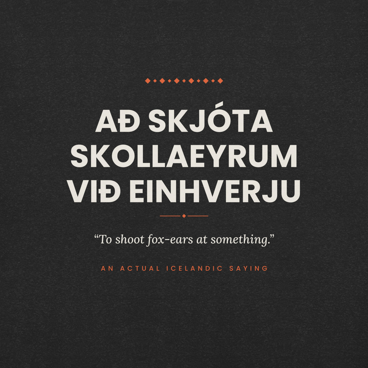 Close-up of the Að skjóta skollaeyrum við einhverju front print, showing cream lettering, English translation and coral accents on Black Heather fabric.