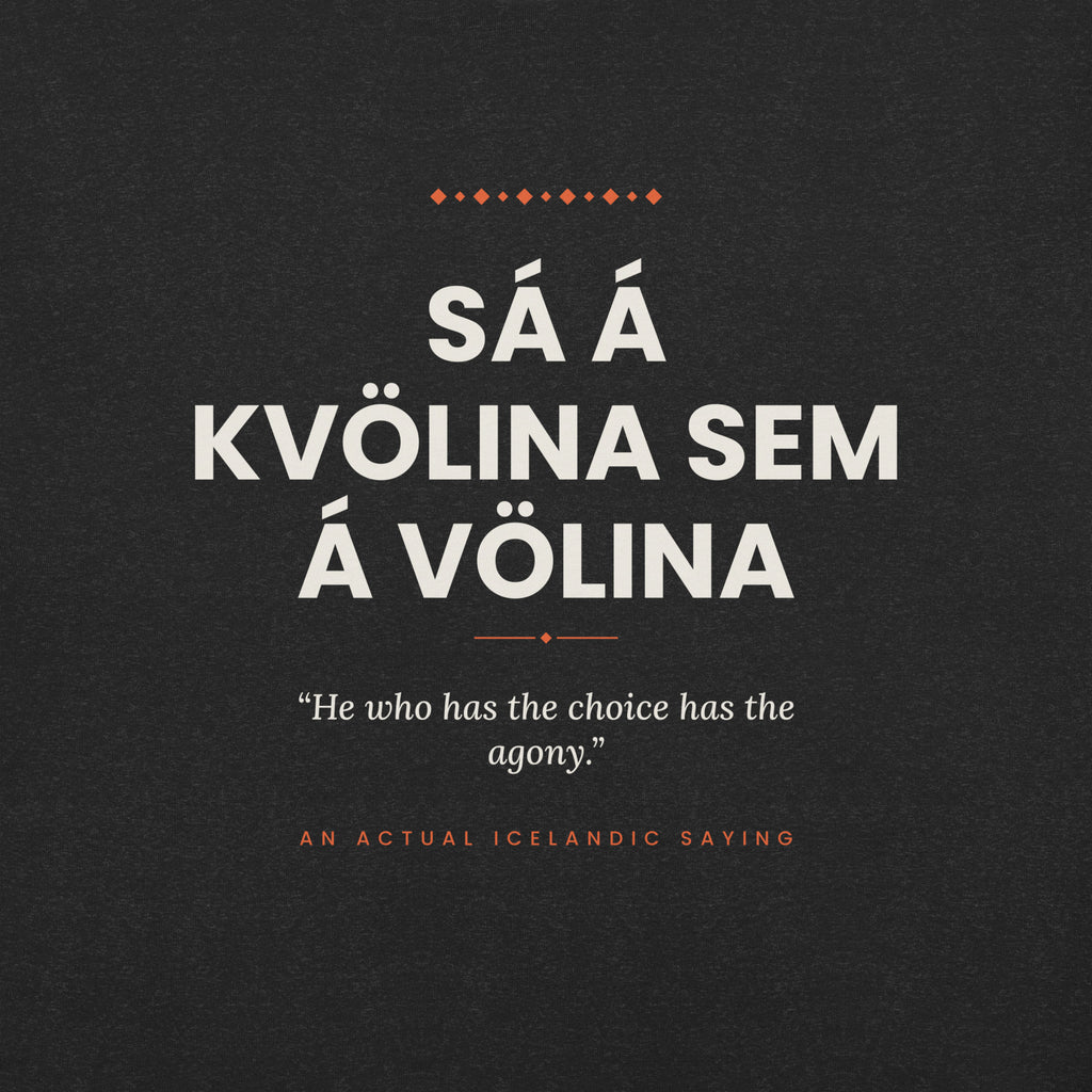 Close-up of the Sá á kvölina sem á völina front print, showing cream lettering, English translation and coral accents on Black Heather fabric.