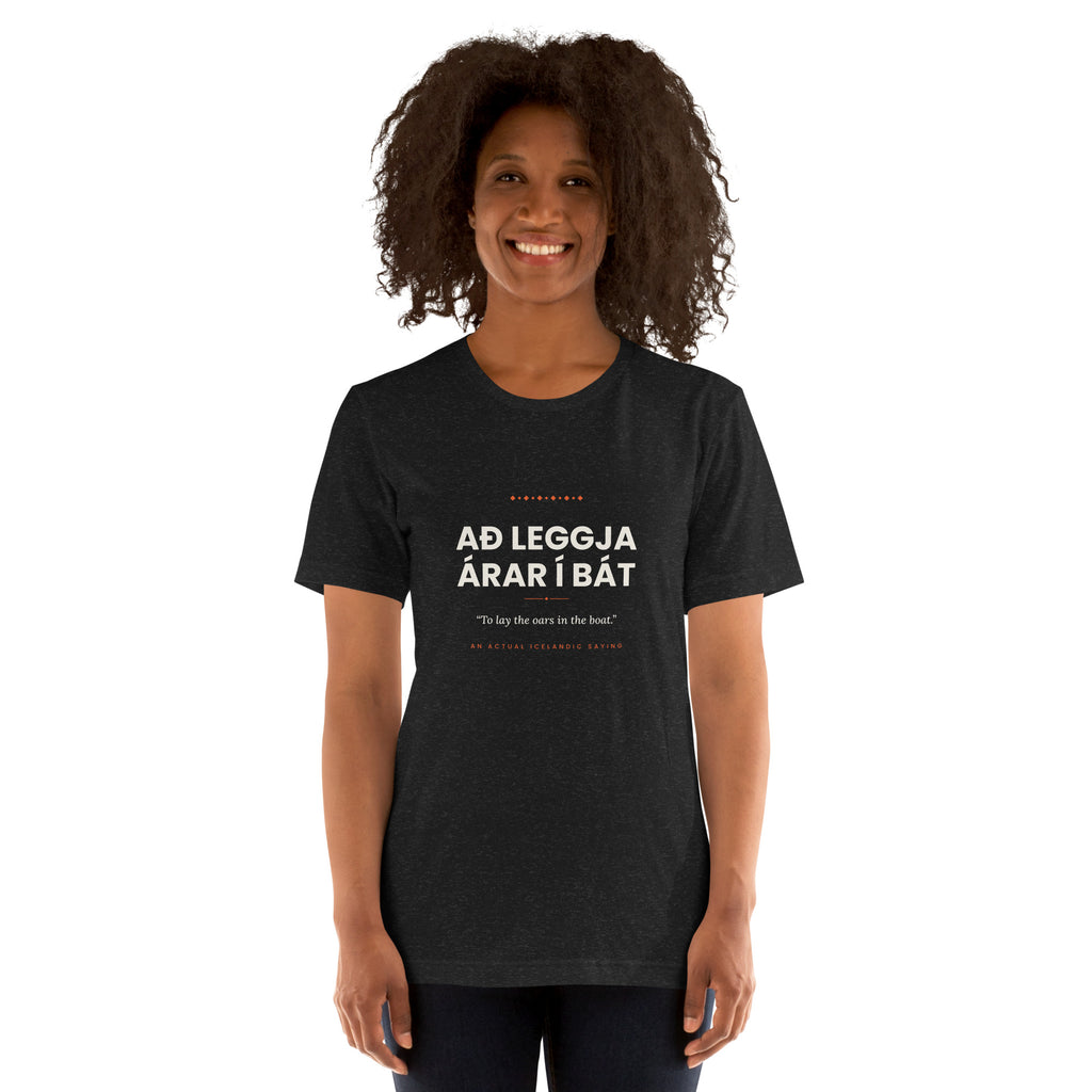 Female model wearing the Black Heather Að leggja árar í bát tee, showing the front print and unisex fit.