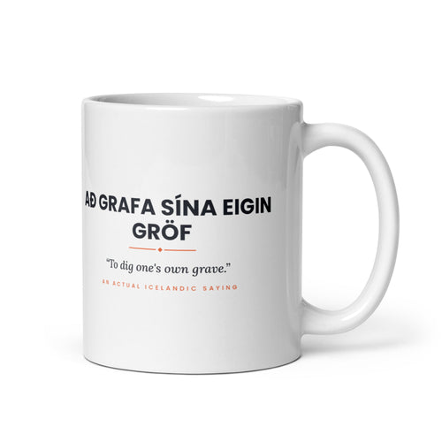 White 11 oz Að grafa sína eigin gröf mug, handle on the right, showing black lettering, English translation and coral accents.
