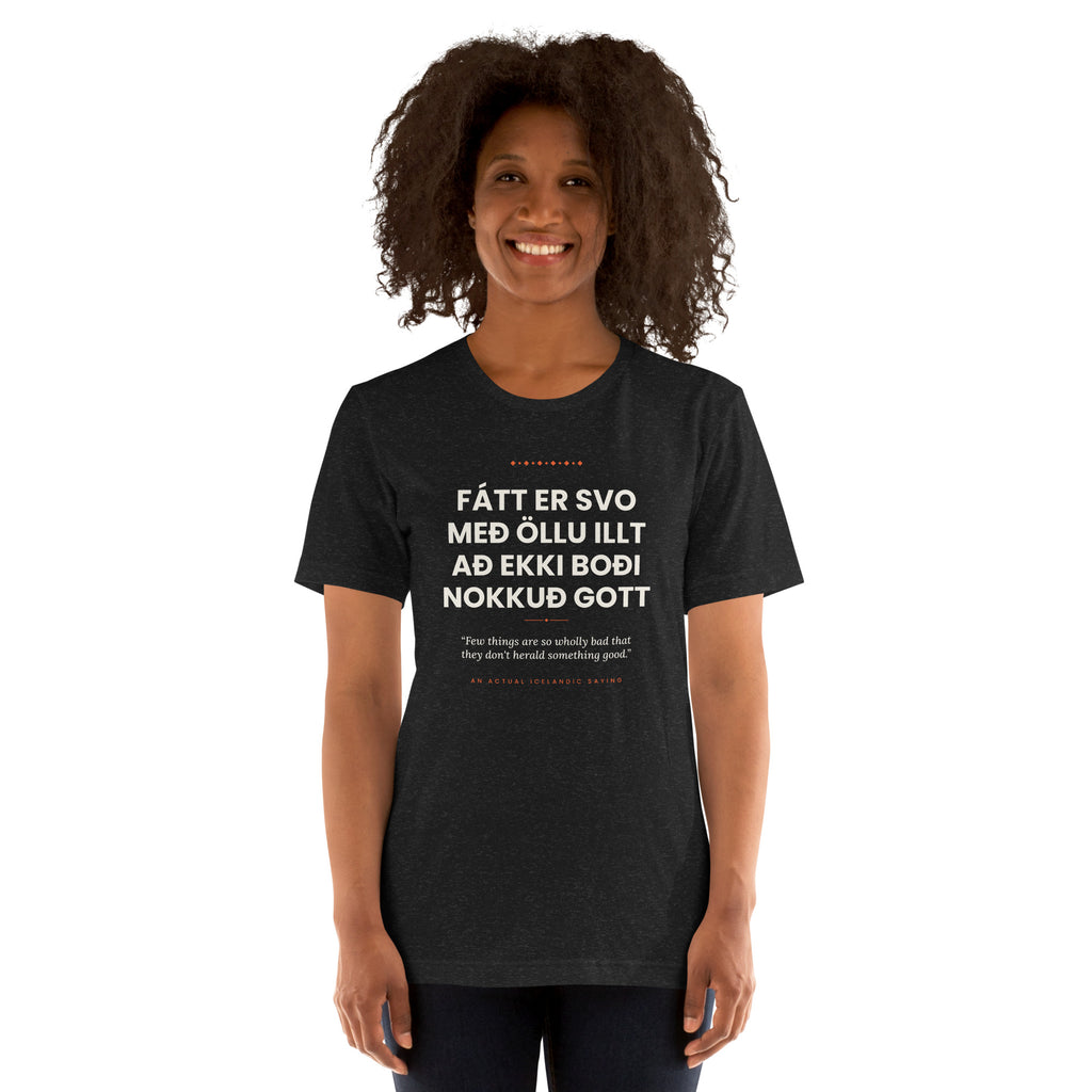Female model wearing the Black Heather Fátt er svo með öllu illt að ekki boði nokkuð gott tee, showing the front print and unisex fit.