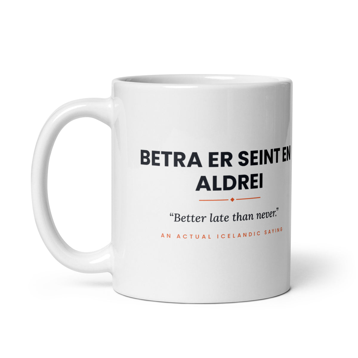White 11 oz Betra er seint en aldrei mug, handle on the left, showing the repeated saying on the other side.