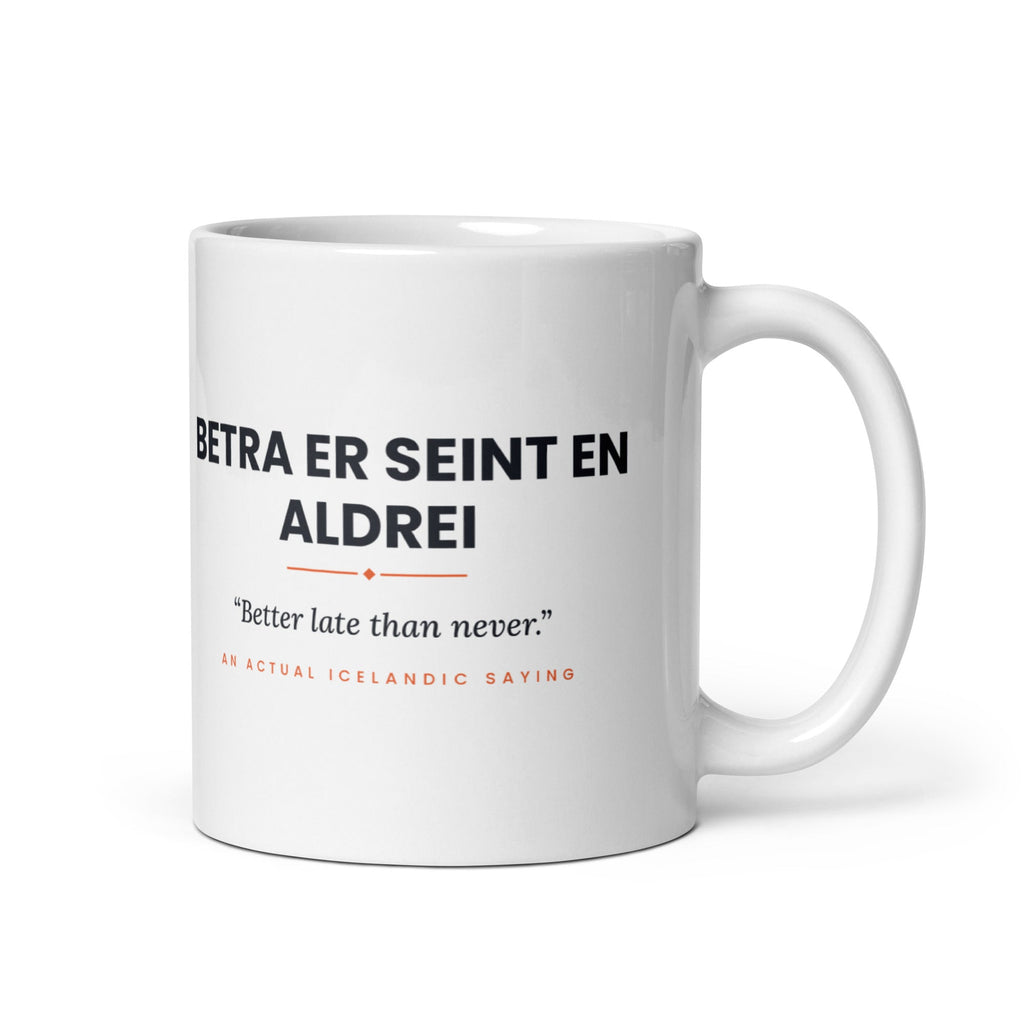 White 11 oz Betra er seint en aldrei mug, handle on the right, showing black lettering, English translation and coral accents.
