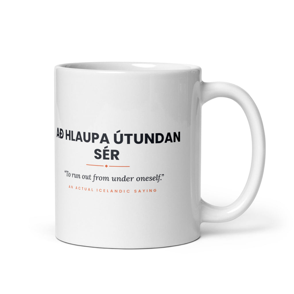 White 11 oz Að hlaupa útundan sér mug, handle on the right, showing black lettering, English translation and coral accents.