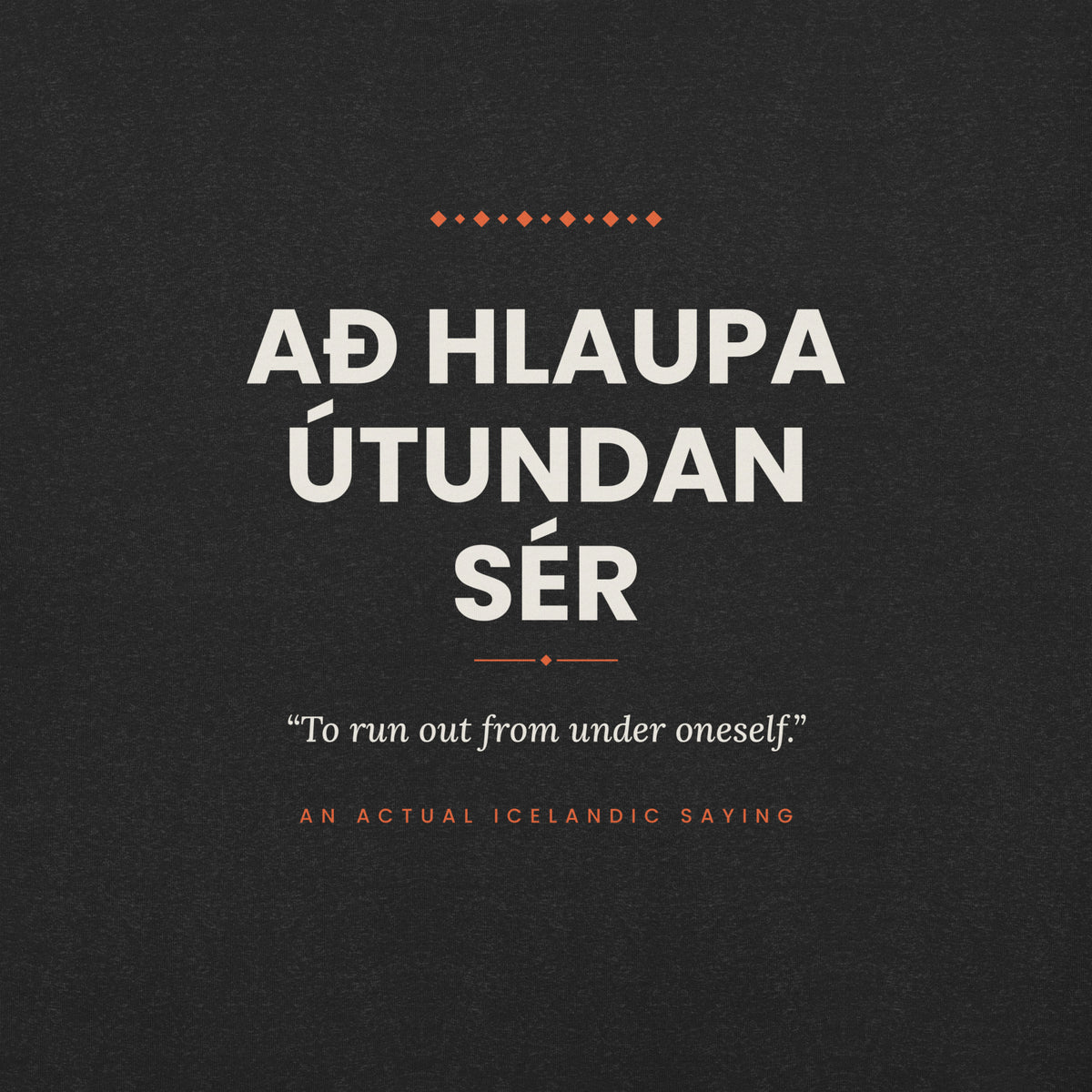 Close-up of the Að hlaupa útundan sér front print, showing cream lettering, English translation and coral accents on Black Heather fabric.