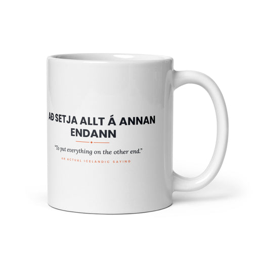 White 11 oz Að setja allt á annan endann mug, handle on the right, showing black lettering, English translation and coral accents.