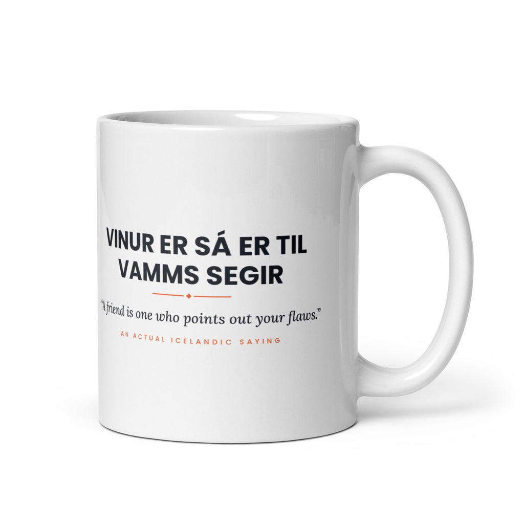White 11 oz Vinur er sá er til vamms segir mug, handle on the right, showing black lettering, English translation and coral accents.