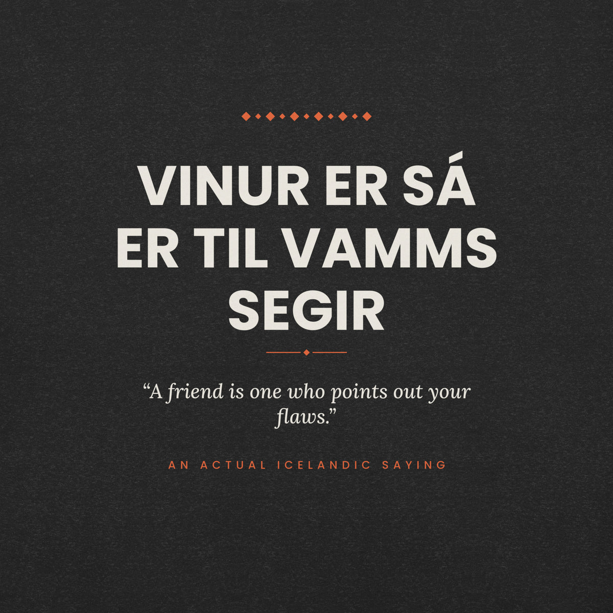 Close-up of the Vinur er sá er til vamms segir front print, showing cream lettering, English translation and coral accents on Black Heather fabric.