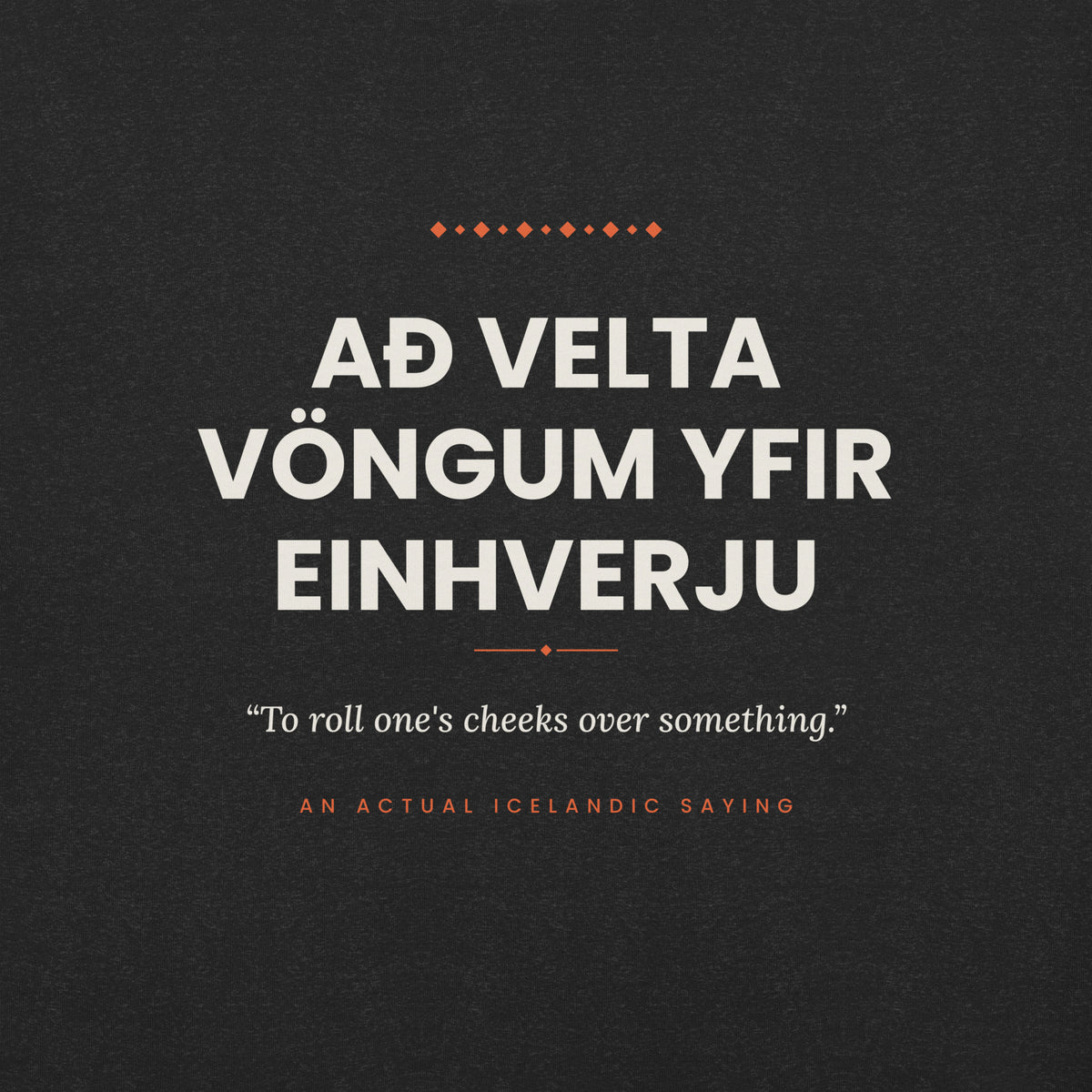 Close-up of the Að velta vöngum yfir einhverju front print, showing cream lettering, English translation and coral accents on Black Heather fabric.