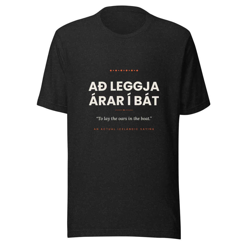 Front view of the Black Heather Að leggja árar í bát tee, with cream lettering, English translation and coral accents.