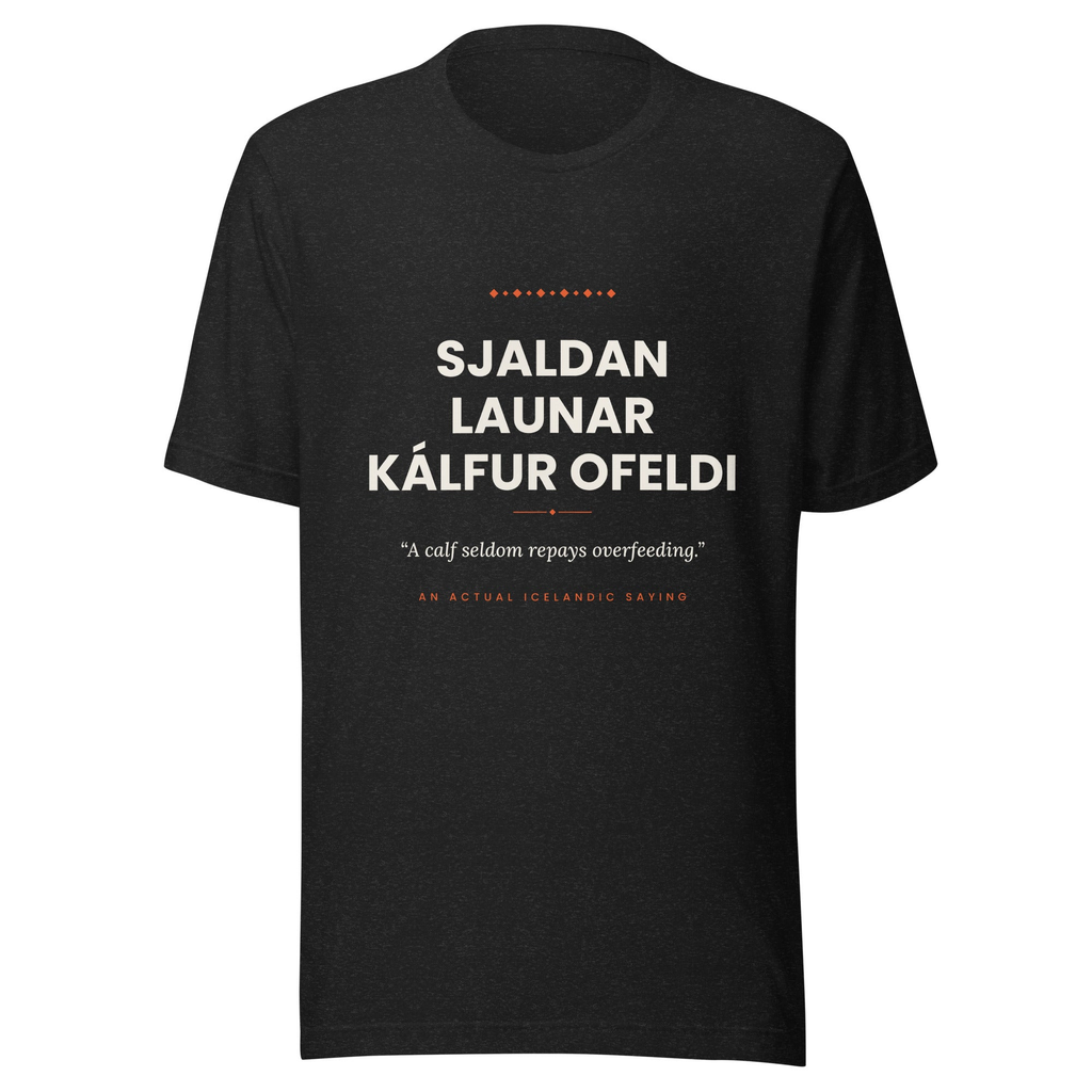 Front view of the Black Heather Sjaldan launar kálfur ofeldi tee, with cream lettering, English translation and coral accents.