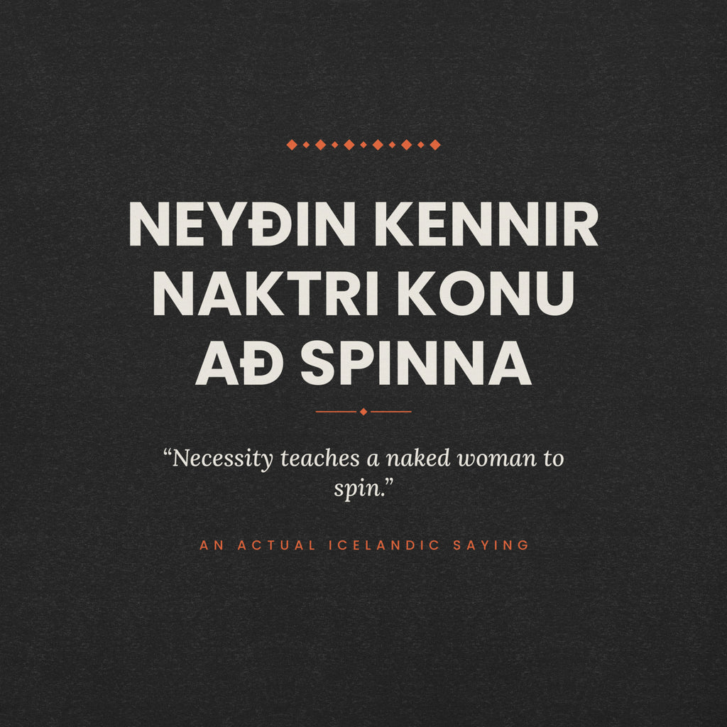 Close-up of the cream Icelandic saying and English translation with coral accents on the Black Heather tee.